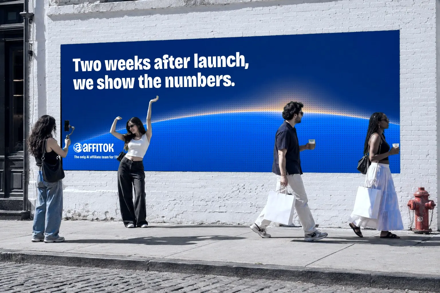 SoHo white brick wall with the affitok mural: the headline Two weeks after launch, we show the numbers. above an early sun over a blue earth; a creator poses while a friend films her on a gimbal, two people with shopping bags and coffee walk past, a red hydrant at right